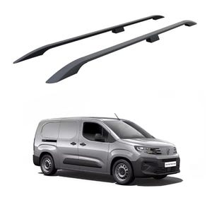 May include: Two dark grey roof rack crossbars above a silver van. The crossbars are curved and aerodynamic, designed for secure attachment to the vehicle's roof. The van has black tyres and a black front bumper.