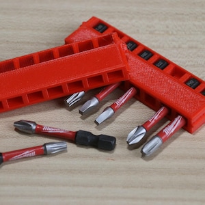 May include: Red plastic storage case with 10 slots for holding screwdriver bits. The case is open and there are five screwdriver bits in the image. The bits are red and silver.