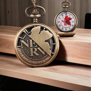 May include: Two antique-style pocket watches with bronze-colored cases. One watch features the text "NERV" and the phrase "GOD'S IN HIS HEAVEN. ALL'S RIGHT WITH THE WORLD." The other watch has a red design and the text "NERV".