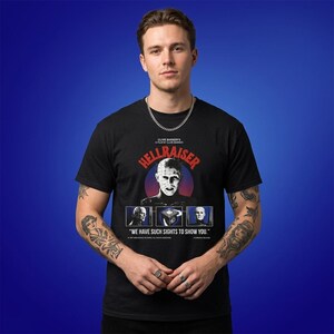 May include: Black t-shirt featuring the movie title "Hellraiser" in red and white, with a central image of a character and the phrase "We have such sights to show you." The shirt is worn by a person.