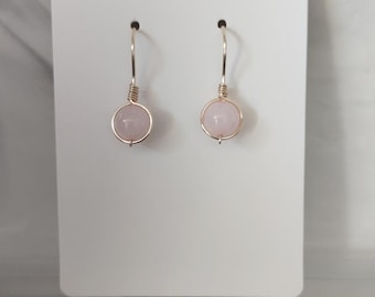 Diverse minimalistische gouden oorbellen met edelstenen, gewikkeld op een draad.