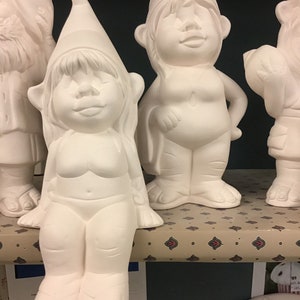 May include: Three white ceramic gnome figurines. The gnome on the left is wearing a hat and has a beard. The gnome in the middle is sitting with its legs outstretched and is wearing a hat. The gnome on the right is standing with its arms crossed and is wearing a hat.