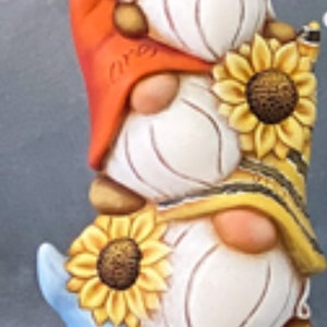 May include: A stacked gnome figurine with three gnomes, each with a white body and a different colored hat. The hats are orange, yellow and blue, and each gnome has a sunflower. The blue hat says "Sunshine".