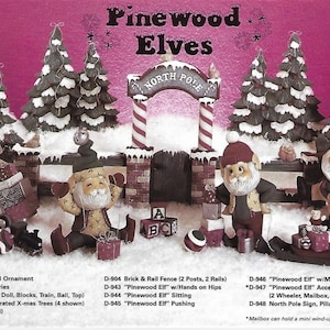 May include: A festive display featuring "Pinewood Elves" figurines in a winter scene. The scene includes snow-covered trees, a North Pole archway, and various elf characters. Accessories include a sled, train, and mailbox. The image has text that lists the product names.