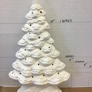 May include: A white ceramic Christmas tree, approximately 12 inches tall, with a textured surface and small holes for lights. The tree has a detailed, layered design and sits on a decorative base.