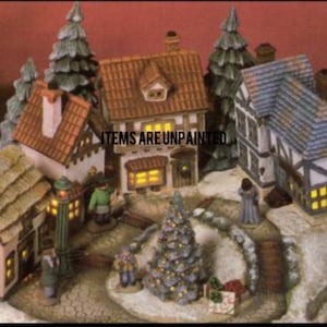 May include: A miniature Christmas village scene with several buildings, including houses with brown and blue roofs, and a church. The scene includes a Christmas tree, street lamps, and figurines. The text "ITEMS ARE UNPAINTED" is visible.