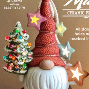 May include: A ceramic gnome figurine with a red knit hat, white beard, and a small Christmas tree. The gnome holds star-shaped ornaments. The text on the image reads "Olaf Lg. Gnome w/Tree 14.75"T x 12" W".