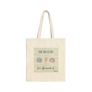 May include: A beige canvas tote bag featuring a graphic print of three seashells centered above wavy horizontal lines. The text reads THE SEA IS HIS for He made it and PSALM 95:5 in dark green lettering. The bag has two matching shoulder straps.