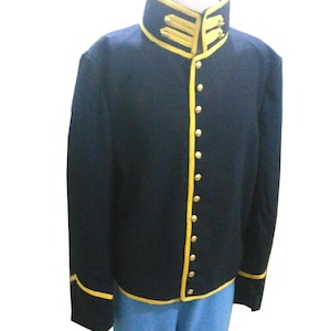 Peut inclure: Une veste militaire bleu marine avec des bordures et des boutons dorés. La veste a un col montant avec des accents dorés et est associée à un pantalon bleu clair. La veste présente des bordures dorées sur les bords et les poignets.