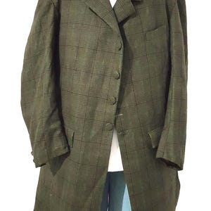 Puede incluir: Un blazer largo a cuadros verde oliva con solapa de muesca y tres botones. El blazer tiene dos bolsillos delanteros y un bolsillo en el pecho. Debajo se ve una camisa blanca con cuello. El blazer se combina con pantalones azul claro.