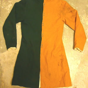 May include: A two-toned garment, half dark green and half orange, with a high collar and long sleeves. The garment has a button closure down the front and appears to be made of a heavy fabric. The sleeves have white cuffs. The garment is likely historical or theatrical attire.