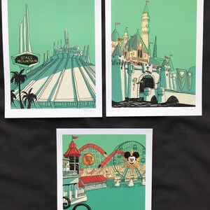 May include: Three vintage-style illustrations of Disneyland attractions. The first shows Space Mountain with the iconic sign. The second shows Sleeping Beauty's Castle with a moat and bridge. The third shows the Ferris wheel with Mickey Mouse's face on it.