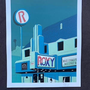 May include: A vintage-style illustration of the Roxy Theatre in Los Angeles, California. The building is painted in shades of blue and green, with a red "R" sign above the entrance. The marquee reads "ROXY" in red and white letters, with the text "BRUCE SPRINGSTEEN THE E STREET BAND" below. The number "3009" is visible on the building.