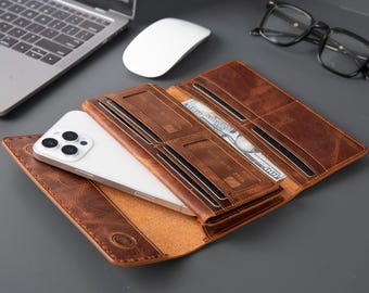 Op de afbeelding: Open bruin leren portemonnee met meerdere kaartsleuven en een compartiment met een smartphone en een biljet van 100 dollar. De portemonnee is open en toont het interieurontwerp en de inhoud. Het leer heeft een distressed afwerking.