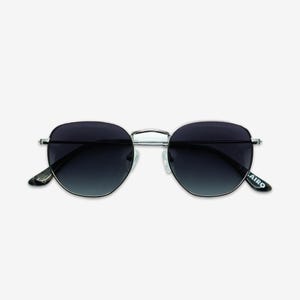 May include: Silver-framed sunglasses with dark, gradient lenses. The sunglasses have a rounded, geometric shape and a subtle, modern design. The temples feature the brand name "LAIRO".