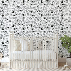 Pode incluir: Papel de parede preto e branco com um padr&atilde;o repetido de rostos de c&atilde;es. Um ber&ccedil;o branco com um colch&atilde;o branco e um cobertor branco est&aacute; na frente do papel de parede. Um pequeno cavalo de balan&ccedil;o de madeira est&aacute; no lado esquerdo da imagem. Uma planta em vaso est&aacute; no lado direito da imagem.