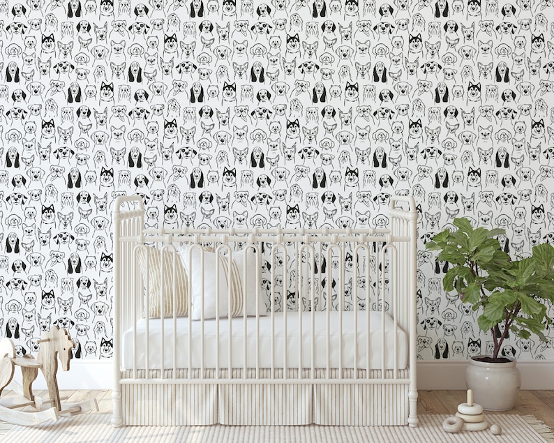 Pode incluir: Papel de parede preto e branco com um padr&atilde;o repetido de rostos de c&atilde;es. Um ber&ccedil;o branco com um colch&atilde;o branco e um cobertor branco est&aacute; na frente do papel de parede. Um pequeno cavalo de balan&ccedil;o de madeira est&aacute; no lado esquerdo da imagem. Uma planta em vaso est&aacute; no lado direito da imagem.