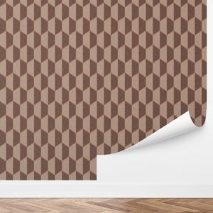 May include: Brown and tan geometric wallpaper with a repeating 3D cube pattern. The wallpaper is partially unrolled, revealing a white backing. The design creates a textured, visual effect.