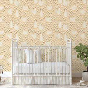 May include: A white crib with a yellow and white chicken patterned wallpaper. The crib has a white mattress and a white blanket. There is a rocking horse in the foreground and a potted plant in the background.