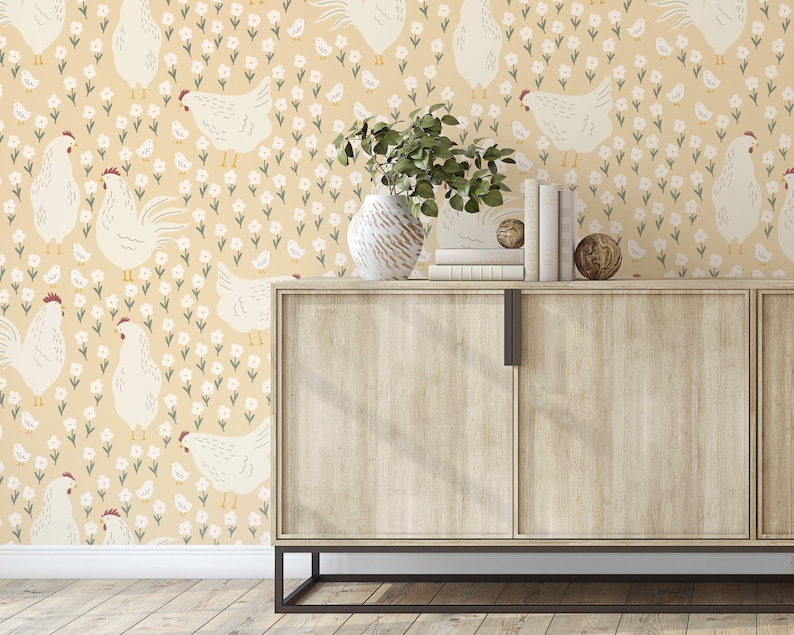May include: A beige wallpaper with a repeating pattern of white chickens and small white flowers. A wooden cabinet with two doors sits in front of the wallpaper. The cabinet has a light wood finish and black metal legs.