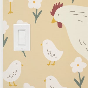 May include: A light switch with a white background and a beige wall with a pattern of white flowers, green stems, and white chicks with yellow beaks. A white hen with a red comb and beak is in the upper right corner.