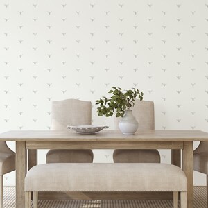 May include: A light wood dining table with four chairs and a bench. The wall behind the table has a white wallpaper with a repeating pattern of gray animal heads.