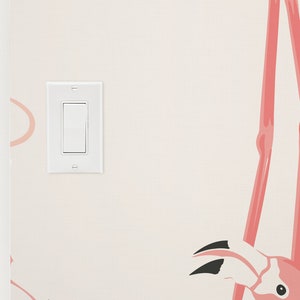 Op de afbeelding: Een witte lichtschakelaar op een muur met een roze flamingo behangpatroon.