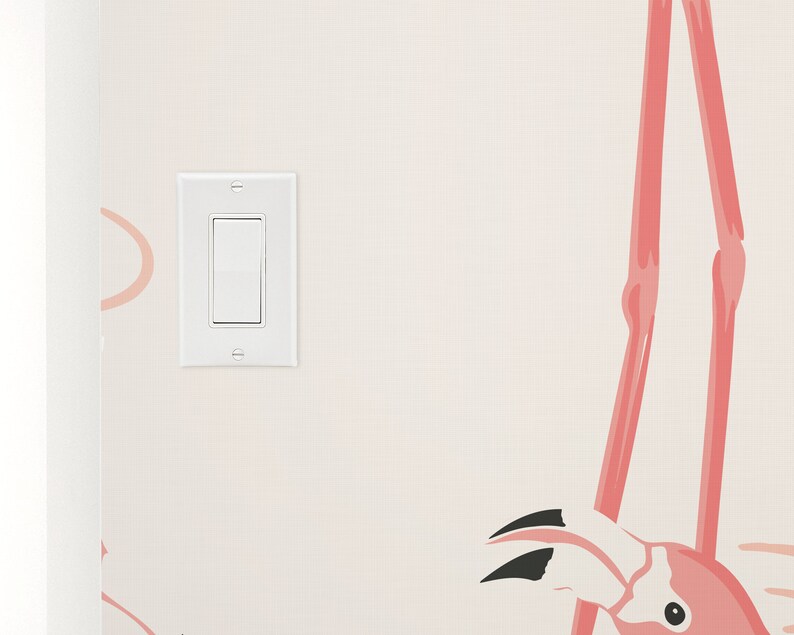 Op de afbeelding: Een witte lichtschakelaar op een muur met een roze flamingo behangpatroon.
