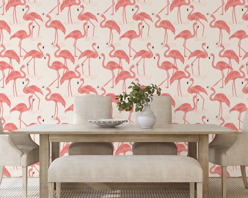 Op de afbeelding: Een witte achtergrond met een herhalend patroon van roze flamingo's. De flamingo's staan in verschillende poses, sommige staan, sommige met hun nek gebogen en sommige met hun hoofd gedraaid. De flamingo's kijken allemaal in dezelfde richting. De achtergrond is licht cr&egrave;mekleurig. De afbeelding is een behang.