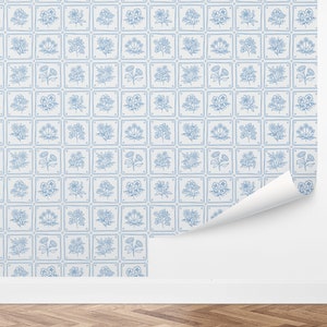 May include: Blue and white floral wallpaper with a repeating pattern of flowers in squares. The wallpaper is shown on a white wall with a corner peeled back.