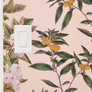 May include: A white light switch with a single toggle switch on a pink wall with a floral wallpaper pattern featuring yellow flowers and green leaves.