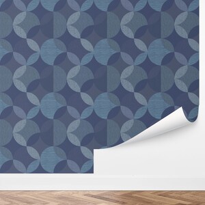 May include: Blue wallpaper with a geometric pattern of overlapping circles in shades of blue. The wallpaper is partially unrolled, revealing a white backing. The design is a modern take on a classic pattern.