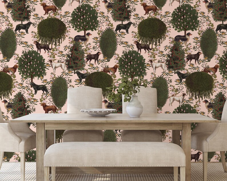 May include: A dining room table set with two chairs and a bench, all upholstered in a cream fabric. The table is made of wood and has a light brown finish. The background is a pink wallpaper with a repeating pattern of dogs, trees, and flowers.