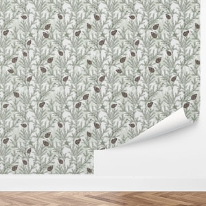 May include: Wallpaper roll featuring a repeating pattern of green pine branches and brown pine cones on a light background. The wallpaper is partially unrolled, revealing a white backing. The design evokes a natural, forest theme.