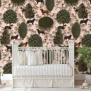 May include: A white crib with a white mattress and a white sheet. The crib is in front of a pink wall with a repeating pattern of green trees and brown dogs.