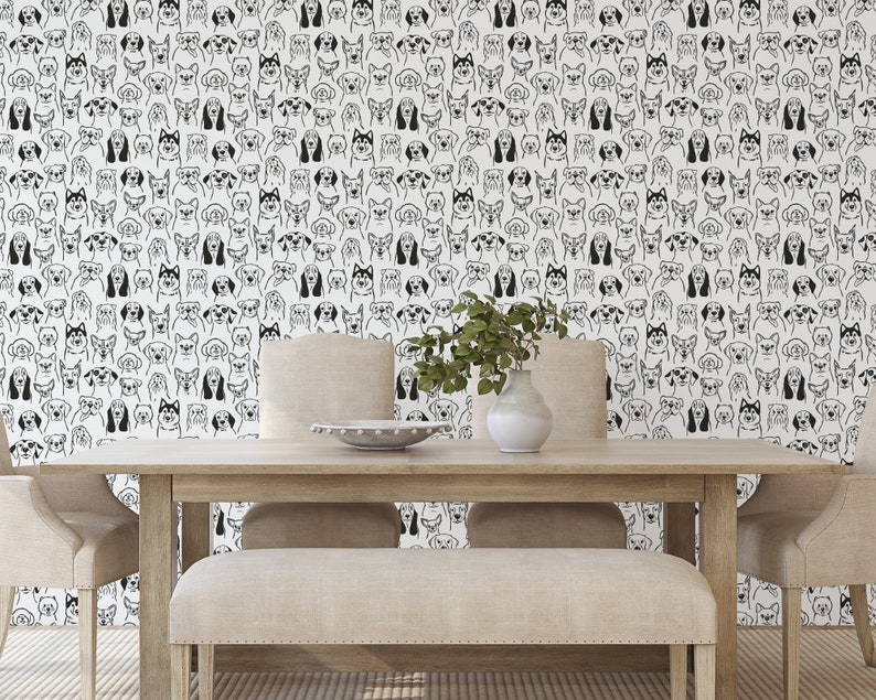 Pode incluir: Uma parede branca com um padr&atilde;o preto e branco de rostos de c&atilde;es. Uma mesa de madeira com duas cadeiras e um banco est&atilde;o na frente da parede. Um vaso com plantas verdes est&aacute; sobre a mesa.