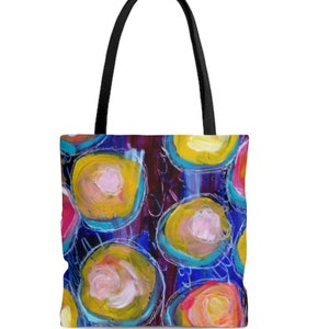 May include: A colorful tote bag with a design of overlapping circles in shades of pink, yellow, blue, and purple on a dark background.