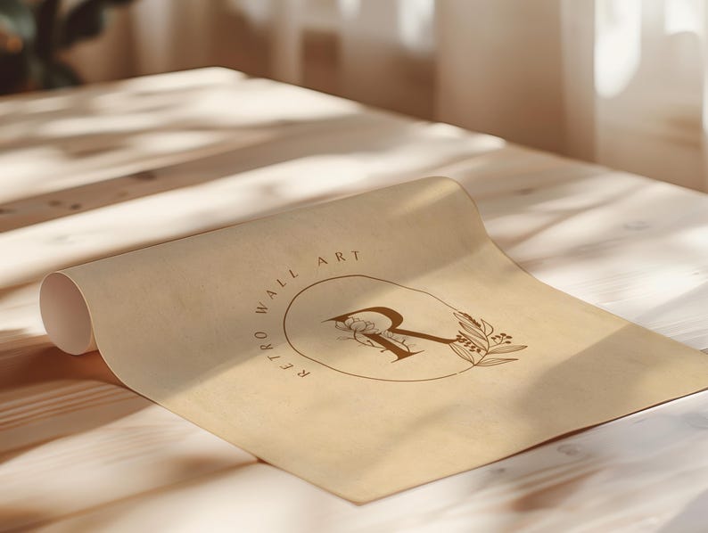 May include: A rolled-up sheet of tan paper with the words "RETRO WALL ART" encircling a floral design and the letter "R". The paper is lying on a light-colored wooden surface.
