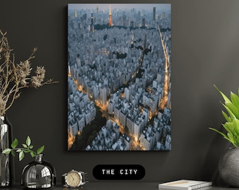 May include: An aerial view of a cityscape at dusk. The image features a dense arrangement of buildings in shades of gray and white, with illuminated streets creating streaks of light. The text "THE CITY" is displayed at the bottom.