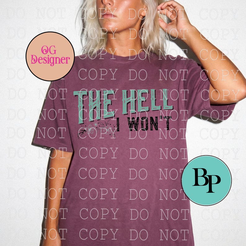 May include: A maroon short-sleeve t-shirt featuring the text THE HELL I WON'T in a combination of teal and black lettering. The design includes small floral accents and a distressed texture. The shirt has a crew neckline and a relaxed fit.