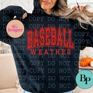 May include: Black hoodie with the words "BASEBALL WEATHER" in distressed red lettering across the front. The hoodie has a drawstring hood and a kangaroo pocket. A casual, sporty apparel item.