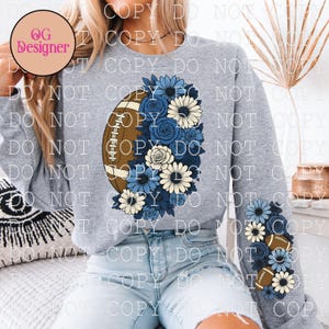 May include: Gray sweatshirt featuring a football design with blue and white floral accents. The football is brown with white stripes. A smaller design of footballs and flowers is on the sleeve.