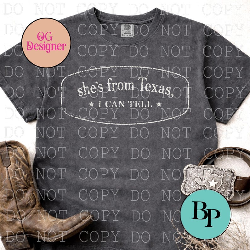 K&ouml;nnte beinhalten: Dunkelgraues T-Shirt mit dem Text "she's from Texas, I can tell" in einem wei&szlig;en Oval. Das Bild zeigt einen braunen Lederg&uuml;rtel mit einer Texas-f&ouml;rmigen Schnalle und braune Cowboy-Stiefel.