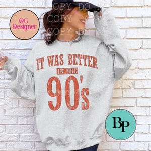 May include: A light gray long-sleeve sweatshirt featuring the distressed red text IT WAS BETTER IN THE 90's printed on the front. The garment has a crew neckline and long sleeves, showcasing a bold, vintage-inspired graphic design across the chest.