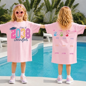 May include: A pink t-shirt dress with the text "class of 2038 Jennifer" in colorful letters. The back of the dress has handprints and numbers from 1st to 12th grade. The girl is wearing pink sunglasses and a headband.