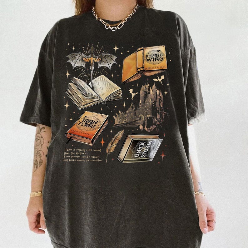 a person wearing a black t-shirt with a graphic design depicting various books and symbols, including a bat, castle, and lightning bolt.