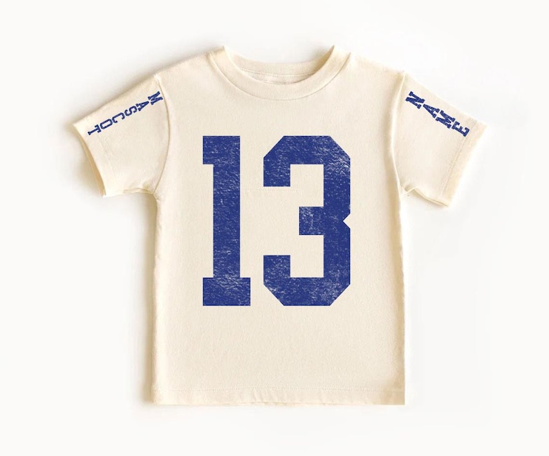 A white t-shirt with the number 13 printed in blue.