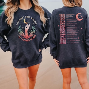 a woman wearing a black sweatshirt with a graphic design on the front and a list of years on the back.