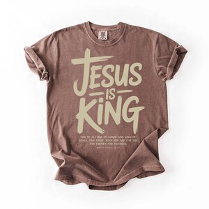 A brown t-shirt with the text "JESUS IS KING" printed on it.