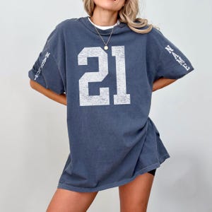 A woman wearing a blue t-shirt with the number 21 printed on it.